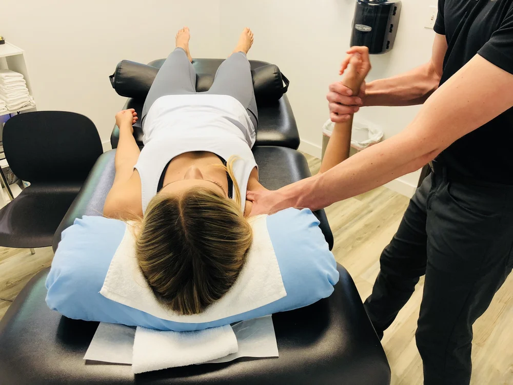A Radius provider performs manual therapy on a patient's shoulder and arm as she lies face-up on the treatment table