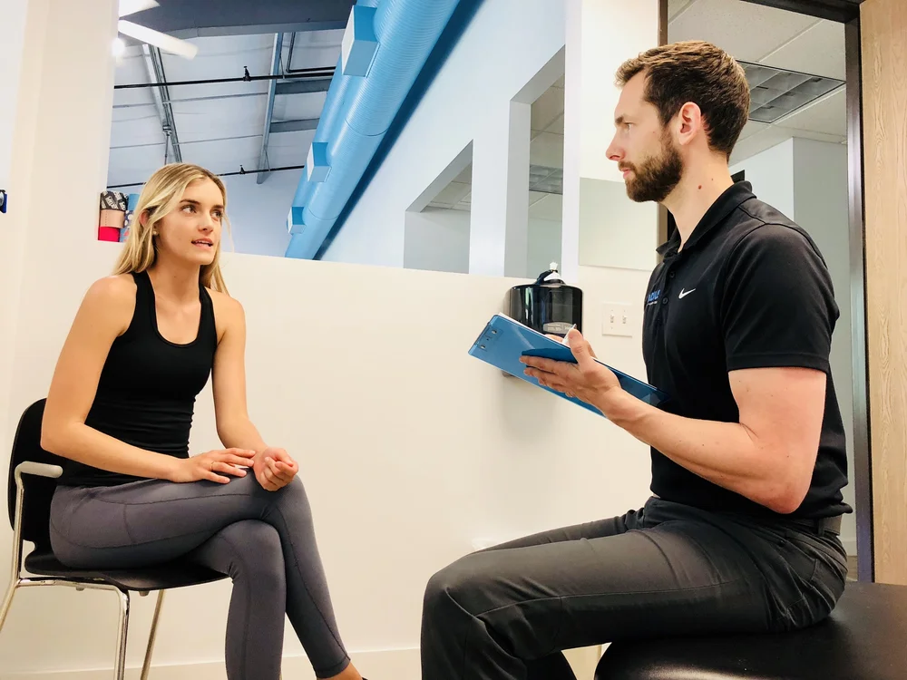 A Radius provider reviews a patient's medical history from a clipboard as she sits and talks with him during her first visit